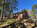 Brick house featuring a front porch and surrounded by mature trees, set against a clear blue sky at 1220 Roanoke Ave, Henderson, NC 27536