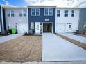Rear exterior view of townhomes with garages, white doors and newly seeded lawns at 2335 Whitewing Ln, Wendell, NC 27591