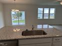 Kitchen island featuring a stainless sink, granite countertops, and an open-concept view to the backyard at 338 Tormore Dr, Homesite 123, Sanford, NC 27330