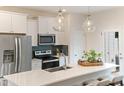 Modern kitchen with stainless steel appliances, quartz countertops, and a stylish eat-in island with pendant lights at 353 Church St # 63, Wendell, NC 27591