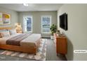 Bright bedroom featuring two windows, a queen-size bed, and a modern dresser with TV for comfortable living at 4 Strowd Ct, Durham, NC 27703