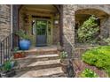 Inviting front entrance features a stone facade, a stylish front door, and decorative plants, creating a welcoming ambiance at 101 Tussled Ivy Way, Cary, NC 27513
