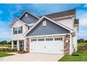 Side view of charming home with stone accents, a two-car garage, and a well manicured lawn at 102 Wilderness Ct, Mebane, NC 27302