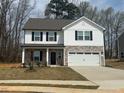 Two-story home featuring stone accents, a two-car garage, black shutters, and a well-manicured lawn at 104 Wilderness Ct, Mebane, NC 27302