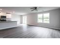 Open-concept living room with vinyl floors, ceiling fan, granite countertops and stainless-steel appliances at 109 Wilderness Ct, Mebane, NC 27302