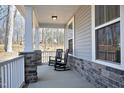 Cozy front porch featuring rocking chairs and stone detailing, a welcoming space for relaxation and enjoying the view at 130 Scarlet Oak Ln, Chapel Hill, NC 27516