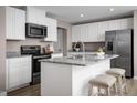 Modern kitchen with white cabinetry, stainless steel appliances, and a granite countertop island with seating at 133 Cavalier Rider Run, Wendell, NC 27591