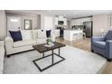 Open-concept living room showcasing modern furnishings and seamless flow into the bright kitchen area at 133 Cavalier Rider Run, Wendell, NC 27591