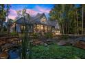 Stunning twilight view of a home with pond and lush landscaping enhanced by warm interior lighting at 140 Winsome Ln, Chapel Hill, NC 27516