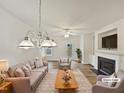 Bright, virtually staged living room featuring hardwood floors, a cozy fireplace, and modern chandelier at 2356 Bay Harbor Dr, Raleigh, NC 27604