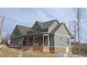 Beautiful gray two-story home with brick foundation, front porch and well-lit windows at 2833 Faucette Ln, Burlington, NC 27217
