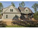 View of a home's exterior displaying vertical siding, gray roof, and well-designed covered porch at 2833 Faucette Ln, Burlington, NC 27217