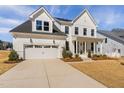 Charming two-story white farmhouse-style home with a manicured lawn and a two-car garage at 3215 Jones Lake Rd, Fuquay Varina, NC 27526