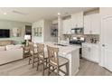 Bright kitchen with white cabinets, stainless appliances, and island with seating overlooking living space at 3401 Rosebush Dr, Zebulon, NC 27597
