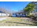 A quaint one-story house with a covered porch area, set against a backdrop of budding trees and a clear sky at 407 Iris Bryant Rd, Dunn, NC 28334