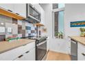 A modern kitchen featuring a black cooktop with stainless steel microwave and wood accents above the countertop at 521 N Mangum St # 12, Durham, NC 27701