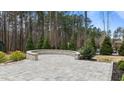 An outdoor patio featuring a stone sitting area overlooking a private, wooded backyard at 8816 Knights Union Way, Wake Forest, NC 27587