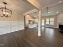 Open-concept living space with hardwood floors, wainscoting, fireplace, and a view into the spacious modern kitchen at 100 Spumante Ct, Princeton, NC 27569