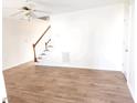 Bright living room featuring wood-look flooring, stairs, a ceiling fan, and neutral paint at 105 Cross Hill Ln, Holly Springs, NC 27540