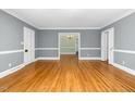 Open living room with hardwood floors, gray walls, white molding, and an elegant entry to dining room at 127 Wilkinson St, Rocky Mount, NC 27804