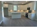 Bright kitchen featuring white cabinetry, a kitchen island, stainless appliances, and hardwood floors at 162 Kirkwall Ln, Selma, NC 27576