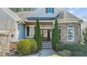 Inviting front entrance framed by manicured greenery, stone accents, and a covered porch with handsome wooden door at 1637 Hasentree Villa Ln, Wake Forest, NC 27587