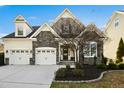 Inviting home featuring a three car garage, stone accents, and manicured landscaping at 2505 Mt Zion Church Rd Rd, Apex, NC 27502