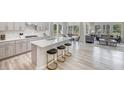 Open concept kitchen features gray cabinets, quartz island with seating, stainless appliances, and seamless flow to living area at 3829 Rosebush Dr, Zebulon, NC 27597