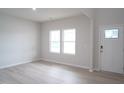 Bright living room with light wood-look flooring, two windows, and a white front door at 3829 Rosebush Dr, Zebulon, NC 27597