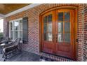 Elegant double front doors with glass panels, brick surround, and charming outdoor seating area at 5712 Kirkwood Park Dr, Raleigh, NC 27612