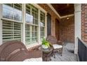 Inviting front porch featuring wicker furniture, brick facade, and classic architectural details at 5712 Kirkwood Park Dr, Raleigh, NC 27612
