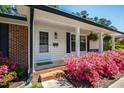 Inviting front porch with colorful azaleas and a cozy seating area at 5920 North Hills Dr, Raleigh, NC 27609