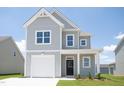 Beautiful two-story home with grey siding, a well-manicured lawn, and an attached garage offers a blend of comfort and style at 71 Furley St, Homesite 116, Sanford, NC 27330