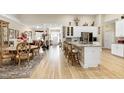 Open-concept kitchen with island seating, white cabinets, stainless steel appliances, and hardwood flooring at 80 Thornwhistle Pl, Garner, NC 27529