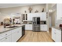 Modern kitchen with granite countertops, stainless steel appliances, white cabinetry, and hardwood floors at 80 Thornwhistle Pl, Garner, NC 27529
