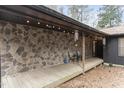 Inviting covered porch featuring stone facade, outdoor seating, string lights, and wooden deck at 118 Flora Mcdonald Ln, Cary, NC 27511