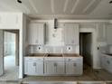 An incomplete kitchen featuring gray cabinets and stainless steel ventilation exemplifies a new home's blank canvas at 1509 Erastus Ct # 48, Fuquay Varina, NC 27526