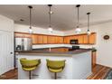 Open kitchen with wooden cabinets, bar seating, and stainless steel appliances at 174 Coalyard Dr, Garner, NC 27529
