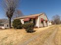 Modest ranch with mature shrubs, siding and awning details on a clear, sunny day at 2116 Mckinney St, Burlington, NC 27217