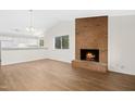 Bright living room featuring a brick fireplace, vaulted ceilings, and an adjacent kitchen area at 292 Cedar Lake Rd # A, Chapel Hill, NC 27516
