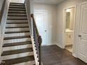 Inviting entryway with hardwood floors, staircase featuring dark wood steps and banister, and a half-bath visible at 3011 Honeymyrtle Ln, Durham, NC 27703