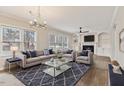 Bright living room with large windows, modern chandelier, fireplace, hardwood floors and stylish furniture and decor at 309 Neuse Ridge Dr, Clayton, NC 27527