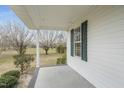 Covered porch detail with white columns, green shutters, and view of the outdoors at 582 Ebenezer Church Rd, Coats, NC 27521
