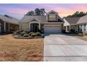 Charming home featuring a stone facade, well-maintained landscaping, and an attached two-car garage at sunset at 1009 Restoration Dr, Durham, NC 27703