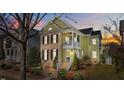 Charming two-story home with yellow siding, brick accents, black shutters, and a welcoming double-decker porch at dusk at 10319 Evergreen Spring Pl, Raleigh, NC 27614