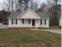 Close-up of a charming single-story home with neutral siding, black shutters, and a cozy, white picket front porch at 1032 Holly Pointe Dr, Wendell, NC 27591