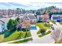 Aerial view of a two-story home with a landscaped front yard in a neighborhood with mature trees at 105 Presley Snow Ct, Holly Springs, NC 27540