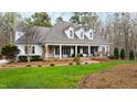 A charming home boasting a covered front porch, lush green lawn, and mature trees at 106 Woodkirk Ln, Chapel Hill, NC 27514