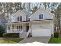 Light blue two-story home with a white front porch, two-car garage, and a well-maintained lawn at 1612 Grappenhall Dr, Apex, NC 27502