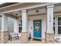 Inviting front porch with seating, brick supports, and a vibrant blue front door with glass inserts at 190 Retreat Dr, Fuquay Varina, NC 27526